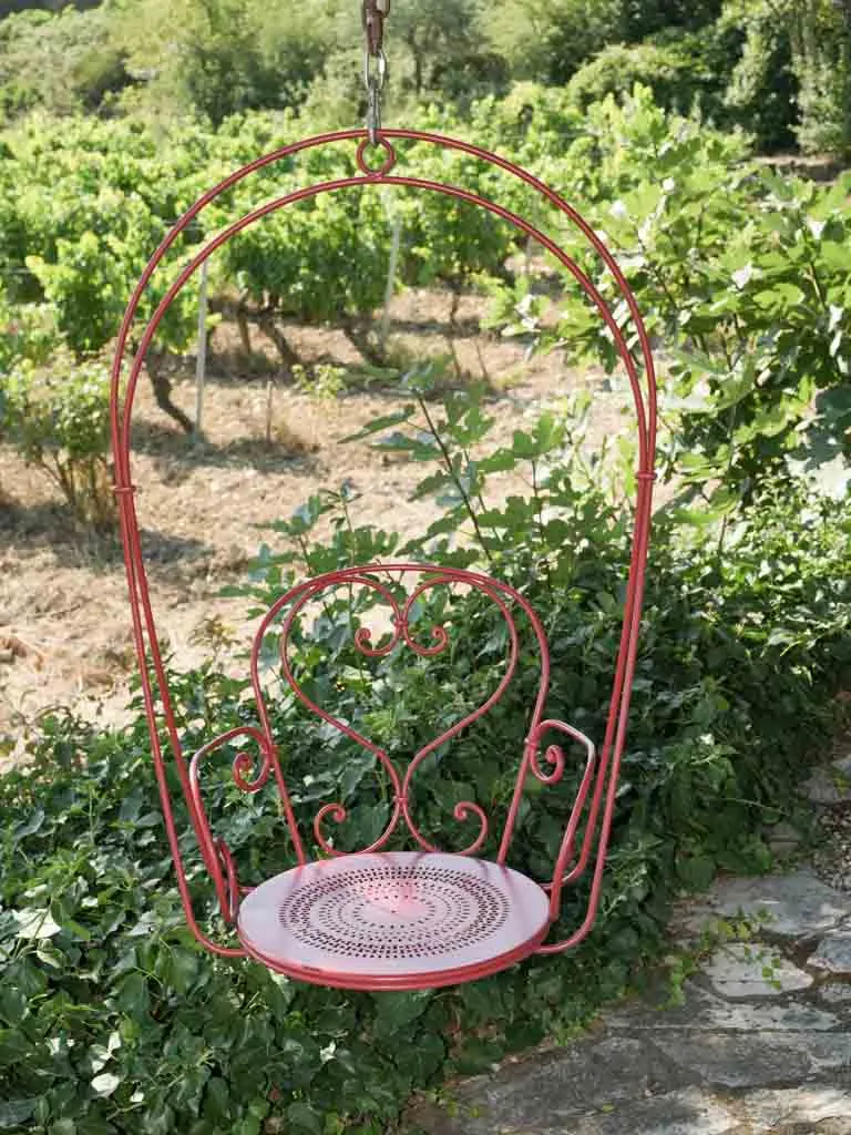 Pair of hanging red metal swings from the oak tree