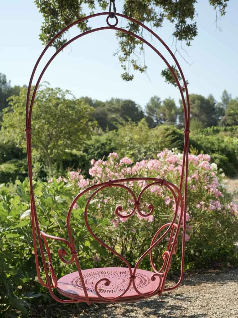 Pair of hanging red metal swings from the oak tree